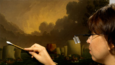 A conservator restoring a historic painting in the ROM's collection.