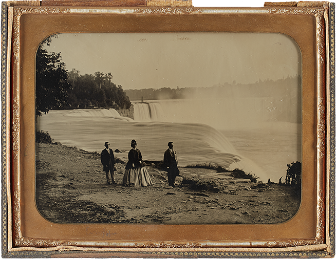 Framed black and white image of three tourists walking beside Niagara Falls
